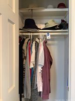 Photo of hanging clothing including sweaters, shirts, and Tilley hats on shelves above