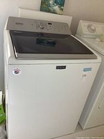 Front view of the Maytag top-load washer showing white body and Maytag badge