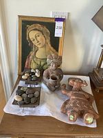 Overview of the portrait painting, the two stone figurines, and two decorative dishes with stones on a white surface showing their spatial arrangement.