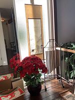 Wide view of the set showing the tall roll-up picture, artificial Christmas plant with red poinsettia, and partial view of the iron wind chime.