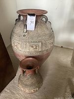Two carved ceramic vases in clay colors with detailed patterns, displayed on carpet.