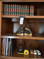 Bookshelf with leather-bound books, Tom Bennett metal bookends in abstract shape, books, VHS holders, Holland shoe decor and ceramic vase visible