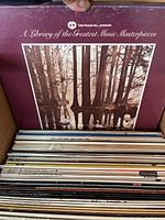 View of vinyl records in open box showing album titled 'A Library of the Greatest Music Masterpieces' and other assorted records