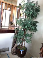 Artificial tree plant about 78 inches tall in dark brown pot with moss on base, displayed upright near a window and stair railing.