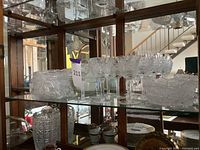 Shelf showing Bohemian Czech crystal in the form of bowls and wine glasses with intricate cut patterns.