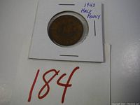 Photo of the 1943 Half Penny coin in protective holder with handwritten note