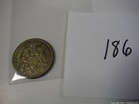 Back side of the coin showing texture and edge details with card number 186 nearby.