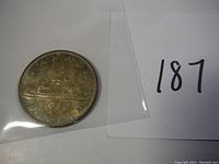 Photo of the 1961 Canadian silver dollar coin in a plastic sleeve, showing its obverse with the year 1961 and the canoe design.