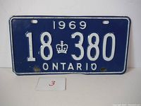 Front view of 1969 Ontario license plate with number 18 380 showing blue background, white embossed characters, and crown symbol.
