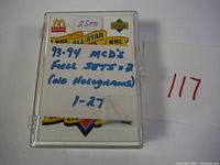 Plastic case with handwritten note showing '2 Sets 93-94 McD's Full Sets #2 (No Holograms) 1-27' labeling the contents of one set of cards.