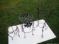 Three metal plant stands on white board outdoors, showing overall condition and scale.