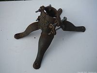 Side and angled view of antique cast iron Christmas tree stand showing three legs and tightening bolts