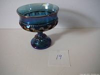 Blue iridescent carnival glass bowl on pedestal with rounded dot pattern, shown from front view