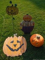 All four Halloween decoration items arranged on grass: three metal and one foam light-up pumpkin figure