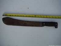 Photo showing the rusty machete with a tape measure above it, indicating its length around 18 inches.
