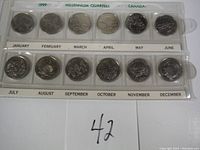 Full view of 12 Canadian Millennium Quarters for 1999 in plastic holder labeled with months and year.