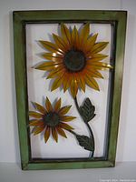 Full frontal view of metal wall art framed piece with two sunflowers and leaves inside a green distressed frame.