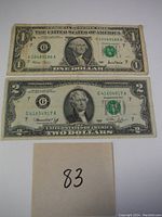 Top view of $1 and $2 U.S. bills with visible serial numbers and green seals.