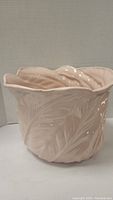Photo of pink ceramic pot showing front side with detailed leaf texture and glossy finish