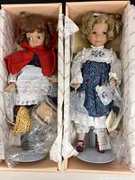 Both Goldilocks and Little Red Riding Hood dolls in original boxes surrounded by branded tissue paper with accessories and CoAs visible.