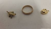 Overview of all three lot items: ring in center, frog charm at left, whale charm at right.