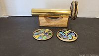 Brass kaleidoscope with stained glass plates on a wood stand shown from side angle, depicting the overall setup and materials.