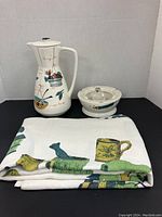 Photo showing the coffee pot, ashtray and folded vintage linen tablecloth together.