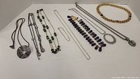 Full view of all 8 necklaces showing variety of designs, metals, and beads.