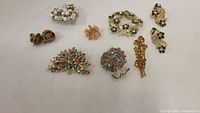 Overview of all rhinestone brooches and earrings laid out on table showcasing various colorful multi-stone pieces