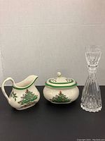 Creamer, sugar bowl, and glass decanter with stopper and measure cup arranged side by side against white background.