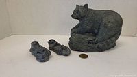 Large raccoon figurine and two smaller otters with coin for size reference.