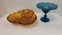 Both amber cut glass bowl and blue compote bowl shown side by side on a white background.
