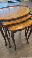 Side view of three nested tables showing scalloped edge tops and carved legs.