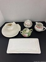 Wide shot of all serveware items: Wedgewood shell plate and cream, RS Germany hand painted sugar bowl, Portmeirion sugar bowl, small Italian platter.