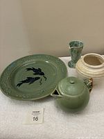 Full view of all four pottery items on a white cloth: Blake charger, green teapot, cream planter, mottled pitcher