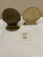 Front and back view of one brass shell bookend showing pitting on base and ridged shell design