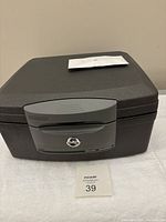 Front view of the black home safe with grey handle and lock closed, keys not shown.