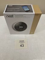 Front view of the box showing Nest Learning Thermostat with digital display and model name