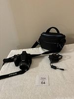 Nikon Coolpix P530 camera with charger and shoulder carrying case laid out on a white surface