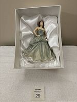 Royal Doulton figurine in original box with white satin lining showing the full figure in seated view.