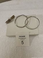 Three sterling silver bracelets displayed on a white surface, showing two narrow bangles and one cuff bracelet.