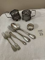 Photo showing the entire lot laid out, including two filigree glass holders, a napkin ring, and five flatware pieces.
