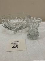 Photo showing the footed bowl and small vase side by side, clear cut lead crystal, intricate starburst and fan patterns on bowl, scalloped rim and detailed cut on vase.