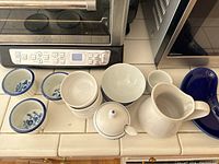 Overview of all ceramic dishes including ramekins, bowls, sugar bowl, and pitcher arranged on counter.