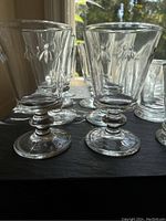 Close-up view of 7 stemmed goblets showing raised bee pattern on clear thick glass.