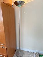 Full view of the tall, slender chrome floor lamp with round base.