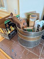Metal tub full of fireplace accessories including bellows, matches in a glass canister, and fire starters.