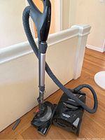 Photo of black Kenmore vacuum cleaner with hose and wand attachments, showing the unit upright with clear view of handle, hose, and base.