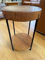 Full front view of the round side table showing wood top, metal legs and lower shelf