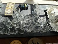 A top down view of all glassware items arranged on a black tray, showing the assortment of glasses and floral etched designs.